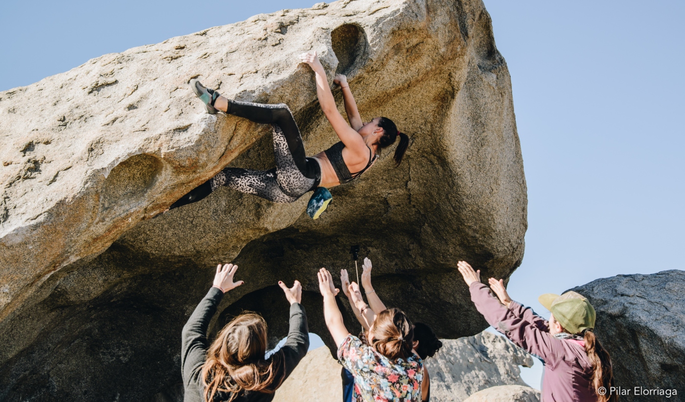Mujeres en ruta. deportista escalando una piedra con ayuda de sus compañeras de la agrupación rockeras
